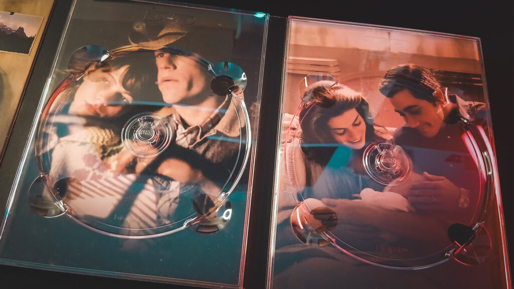 Arte interna do DVD do filme O Segredo Brokeback Mountain | À Esquerda Michelle Williams e Health Ledger abraçados com o bebê. À Direita Anne Hathaway  e Jake Gyllenhaal com um bebê | Dandy Souza